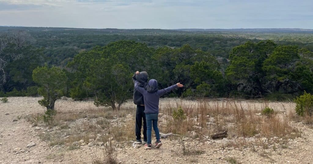 A photo of two children look out over the Texas Hill Country